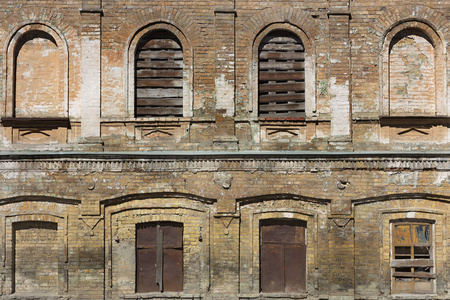 旧房子的门面是复古, 棕色砖墙和拱形窗户登上木板和生锈的铁