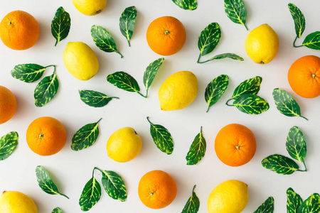 创意夏日图案由橘子柠檬和绿叶在明亮的背景下制成。水果最小的概念。平躺
