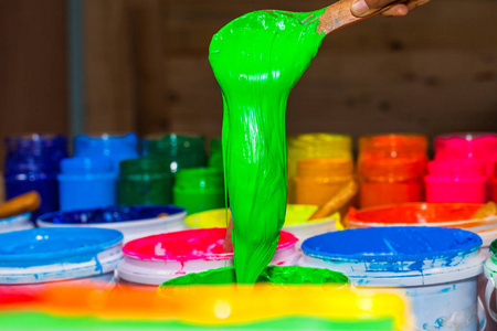 舀出绿色的塑胶墨水, 把桶放在店里。t恤衫厂塑胶墨水的几种颜色主要颜色为蓝绿色黄橙红色和黑色