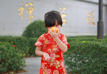 可爱的亚洲孩子女孩在传统中国服饰与华人庙宇在泰国曼谷举行神圣的橙色