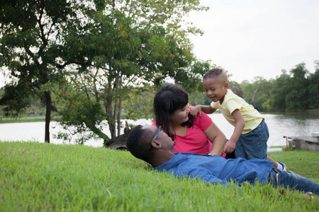 非洲裔美国家庭和小孩放松和打上绿色公园与副本空间