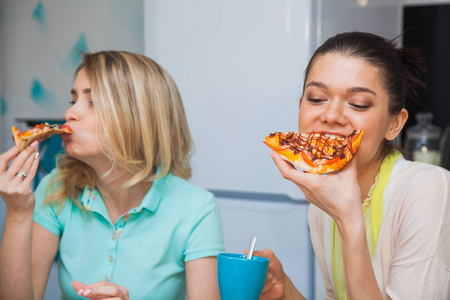 两个年轻女人吃比萨饼。女孩尝尝意大利传统食品