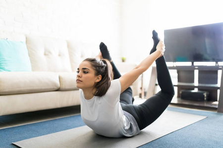 适合年轻女子弯腰和抱腿, 弓姿势瑜伽在家照片