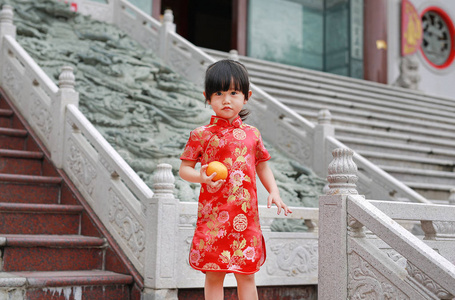 可爱的亚洲孩子女孩在传统中国服饰与华人庙宇在泰国曼谷举行神圣的橙色