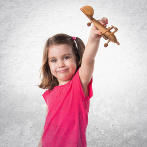 女孩抱着一个木制玩具飞机