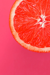 在明亮的背景下的一个柚子片的顶部视图, 浅粉红色的颜色。饱和柑橘纹理图像