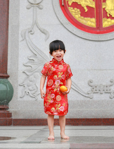 可爱的亚洲孩子女孩在传统中国服饰与华人庙宇在泰国曼谷举行神圣的橙色