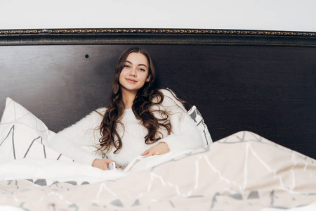 漂亮的睡在白色睡衣的女孩躺在床上清晨, 不想起床, 微笑