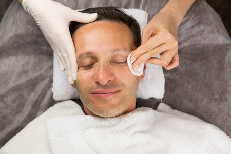 男性的脸,专业的美容师,戴着手套的手照片