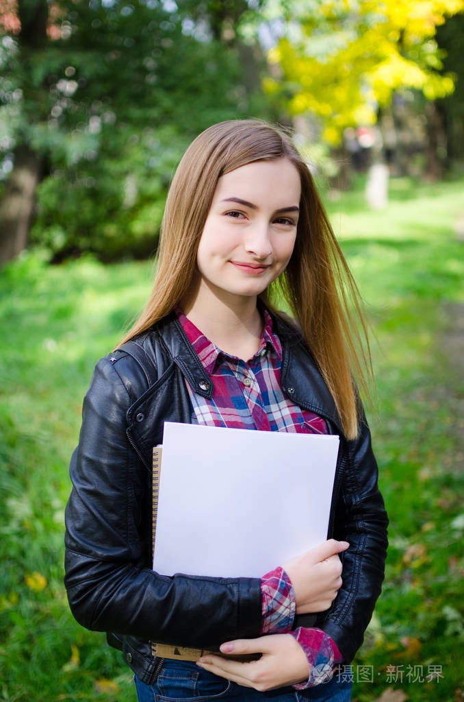白人女学生拿着书.看着摄影机文本或徽标的课本上的空白.复制空间