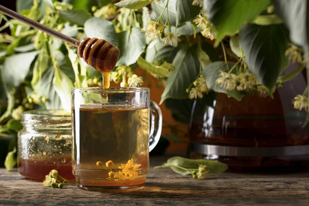 木桌上有蜂蜜和鲜花的椴树茶