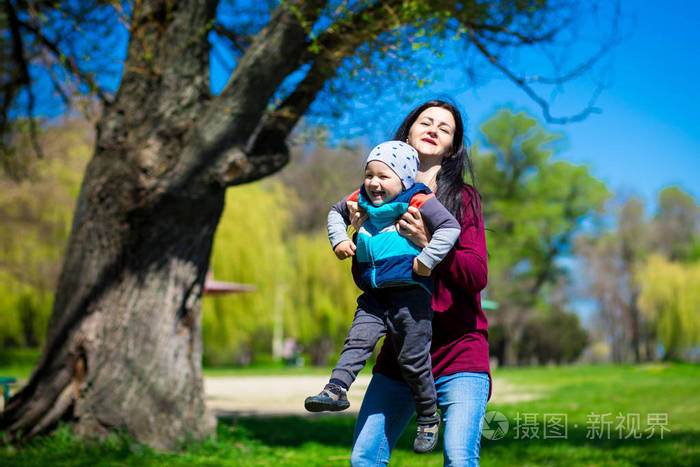 年轻的母亲抱起蹒跚学步的孩子, 全家一起玩得很开心.