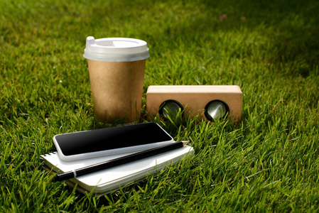 关闭咖啡的视图, 智能手机, 笔记本和音频扬声器绿草