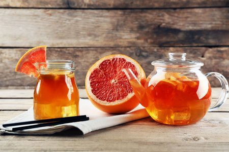 与柠檬和葡萄柚木制背景上的冰的茶