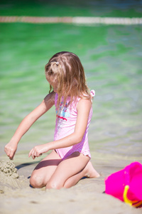 在热带度假期间玩沙滩玩具的小女孩