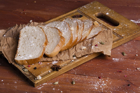 新鲜和芬芳的白面包切片和躺在一个木质的背景。一个小香料已经添加到它, 它也位于牛皮纸。无麸质。概念性食品照片