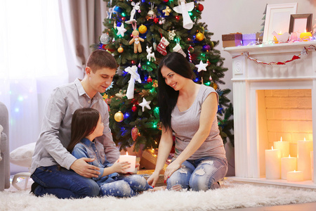幸福的家庭一起装饰圣诞房间里的手中握着蜡烛