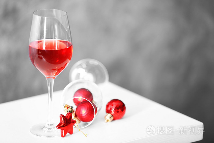 杯红酒与灰色墙上背景上的圣诞饰品