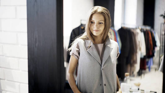 一个年轻女孩正在商店里穿灰色夹克。