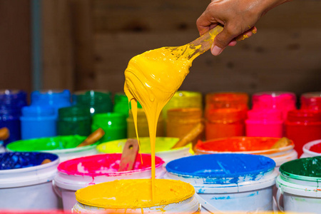 铲黄色的塑胶墨水出桶在商店。t恤衫厂塑胶墨水的几种颜色主要颜色为蓝绿色黄橙红色和黑色