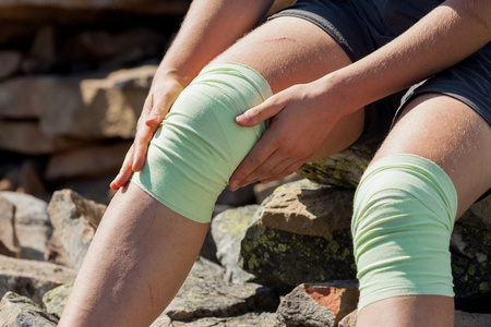 运动员看女孩修复室外的膝盖上的绷带