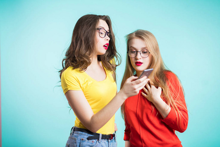 两个漂亮的年轻女孩正在探索智能手机。技术