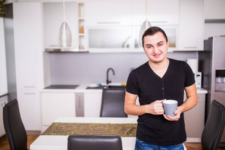 英俊的男人在家庭厨房里喝咖啡的肖像