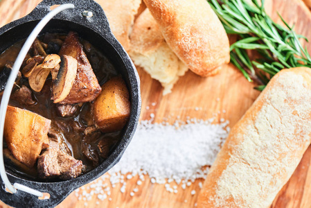 烩蘑菇和调味汁的小牛肉渍在铁锅和硬面包上的木匾上