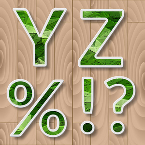 具有阴影效果的现代字母表。绿色叶子在木背景上的字体。YZ 字母标点符号百分比