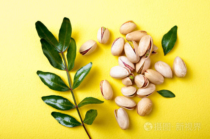 开心果与叶子在黄色背景顶部看法