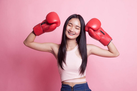 粉红色背景的年轻亚洲妇女与红色拳击手套