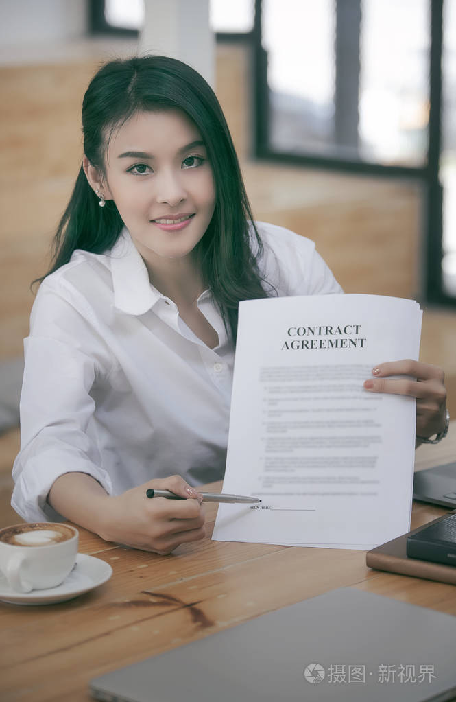 美丽的女商人手持笔指着在办公室里签合同的文件文件照片-正版商用