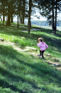 可爱的小女孩跑在森林里的木楼梯。阳光灿烂的日子