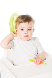 小男孩坐在高脚与板和勺子隔绝在白色背景上