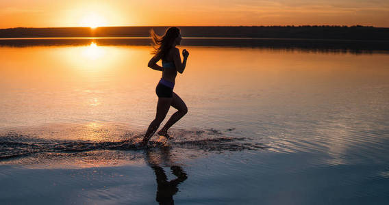 女人在日落时在沙滩上跑