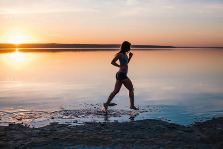 女人在日落时在沙滩上跑