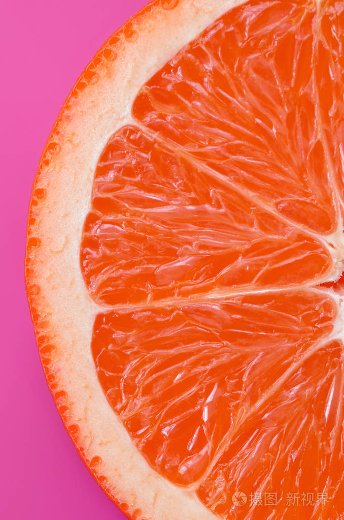 在明亮的背景紫色的一个柚子切片的最高视图.饱和柑橘纹理图像照片-正