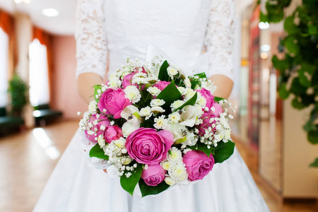 新娘紧握着粉红色玫瑰的美丽婚礼花束