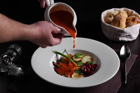 厨师在碗里倒汤.照片