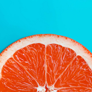 在明亮的背景蓝色的一个柚子切片的最高视图。饱和柑橘纹理图像