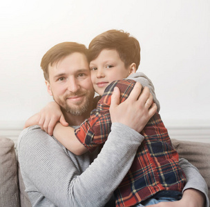 爸爸和他的儿子在沙发上拥抱在家