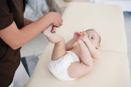 女按摩师给小宝宝做足部按摩。健康生活方式医疗保健理念