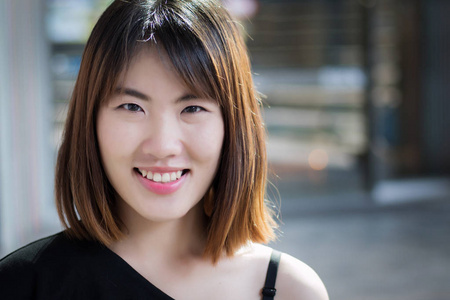 快乐女人笑脸肖像;积极放松的亚洲女性微笑的城市环境;亚洲妇女青年