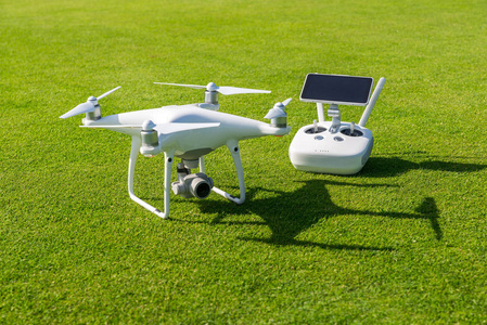 白色专业 quadcopter 无人机遥控从上面对绿色草的背景