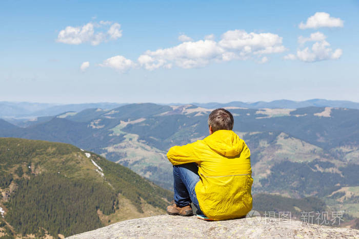 坐在山上的大石头上的人.在山中旅行的概念