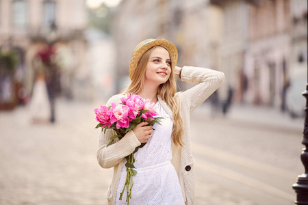 粉红色的花和帽子的年轻金发女郎