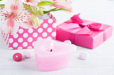 粉红色的百合花与礼品盒。带点蜡烛的贺卡