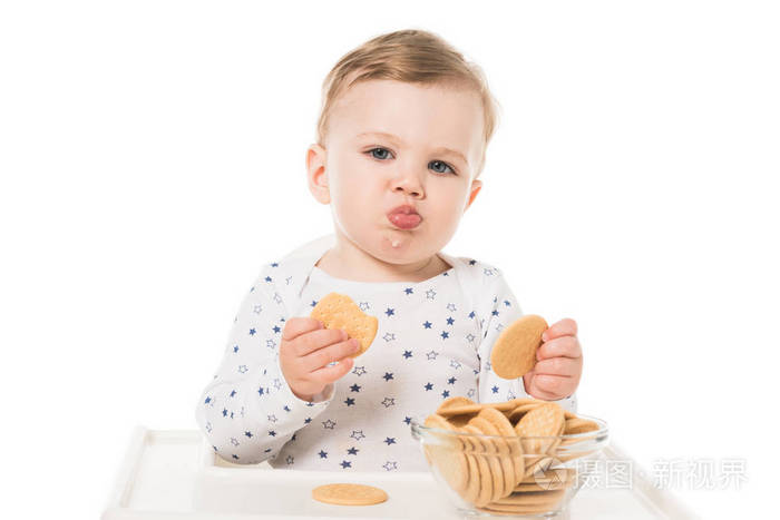 可爱的小男孩吃饼干坐在高脚孤立的白色背景