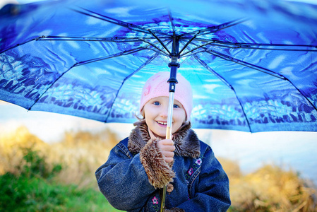 小女孩和男孩用伞在雨中玩。孩子们玩户外时间的阴雨天气在秋天。儿童的秋季乐趣。蹒跚学步的孩子在雨衣和雨鞋走在花园里