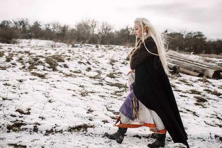 一个美丽的金发女郎在一个黑色的斗篷,维京人的肖像照片